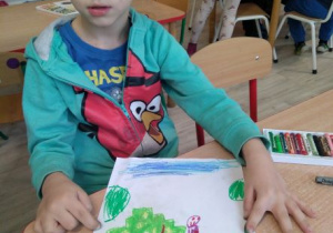 Chłopiec pokazuje rysunek przedstawiający świat wyobraźni